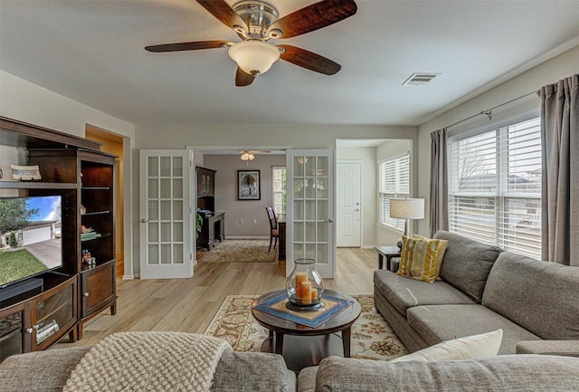 living area with light wood-style floors, french doors, visible vents, and ceiling fan