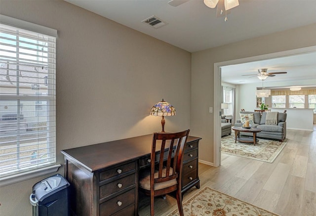 office space featuring light wood-type flooring, baseboards, visible vents, and a ceiling fan