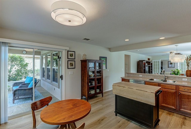 kitchen featuring light wood finished floors, visible vents, light countertops, and a sink