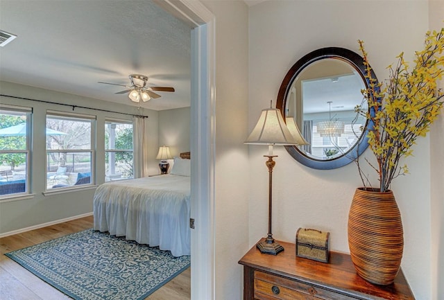 bedroom featuring light wood finished floors, visible vents, and baseboards