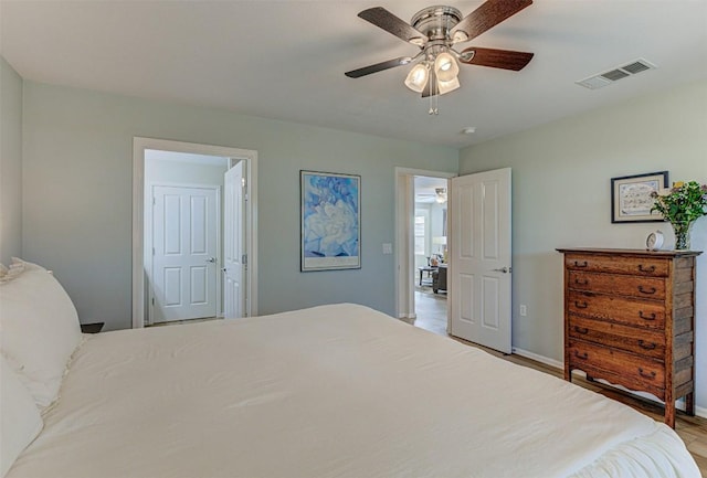 bedroom featuring ceiling fan, wood finished floors, visible vents, and baseboards