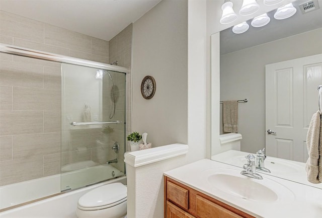 bathroom with visible vents, vanity, toilet, and combined bath / shower with glass door