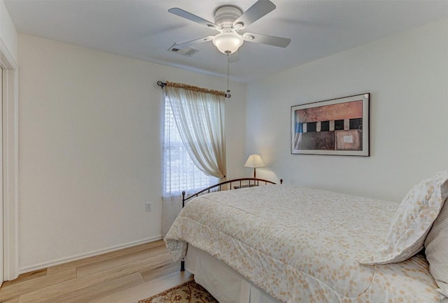 bedroom featuring a ceiling fan, baseboards, visible vents, and wood finished floors