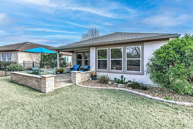 rear view of house featuring a patio area, a yard, fence, and stucco siding