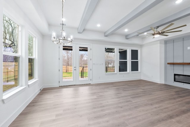 interior space featuring a wealth of natural light, beam ceiling, a glass covered fireplace, and light wood-style flooring