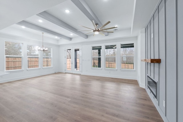 unfurnished sunroom with a fireplace, beamed ceiling, and ceiling fan with notable chandelier