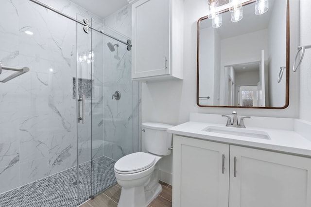 bathroom featuring a marble finish shower, baseboards, toilet, wood finished floors, and vanity