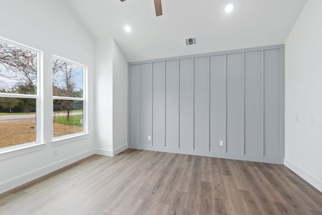 empty room featuring lofted ceiling, light wood-style flooring, visible vents, and ceiling fan