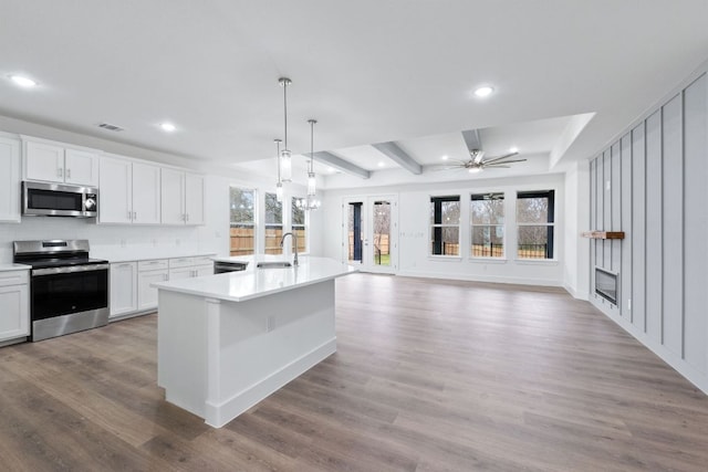 kitchen featuring stainless steel appliances, wood finished floors, light countertops, and white cabinets