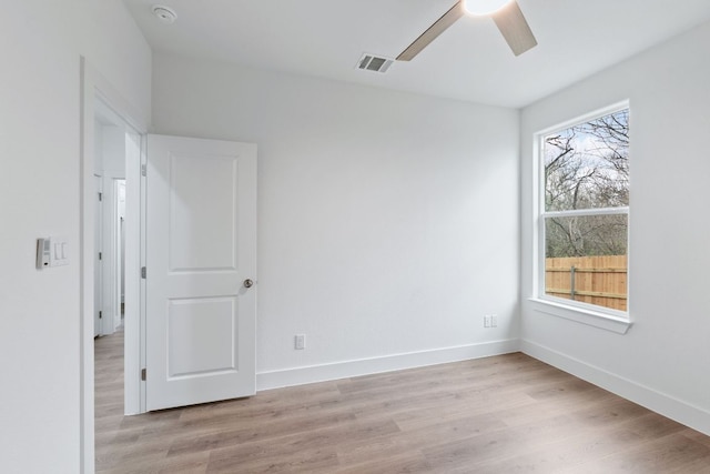 spare room with light wood finished floors, ceiling fan, visible vents, and baseboards