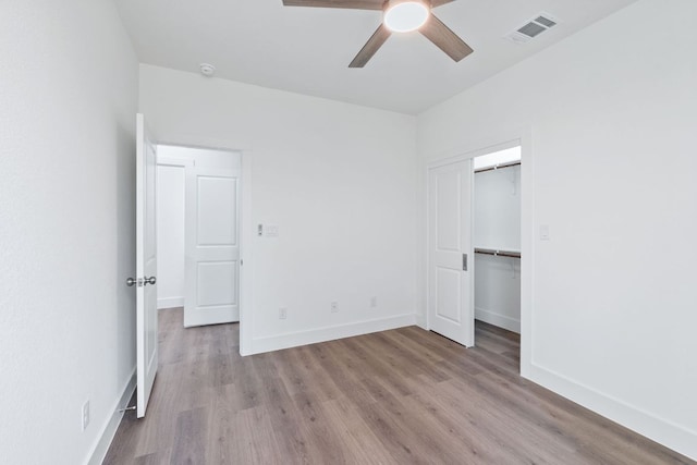 unfurnished bedroom featuring baseboards, visible vents, ceiling fan, and wood finished floors