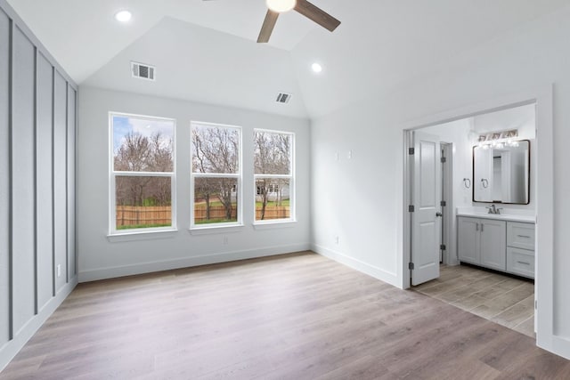 unfurnished bedroom featuring vaulted ceiling, light wood finished floors, visible vents, and baseboards