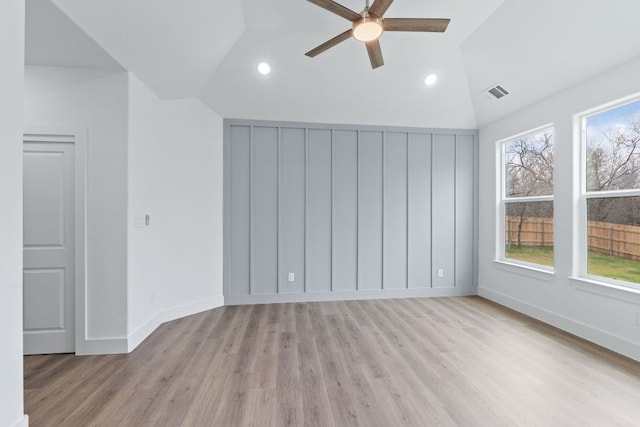 spare room featuring light wood finished floors, visible vents, vaulted ceiling, ceiling fan, and baseboards