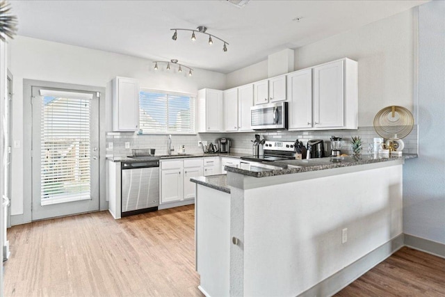 12185 Chelsea Glen Place Br, Austin, TX 78753 - kitchen with stainless steel appliances, white cabinetry, a peninsula, decorative backsplash, and light wood-style flooring