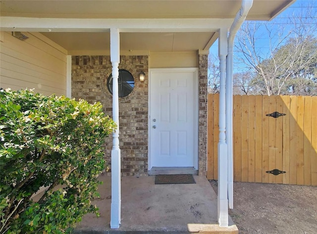 entrance to property featuring brick siding and a gate