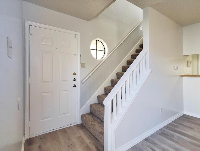 staircase with baseboards and wood finished floors