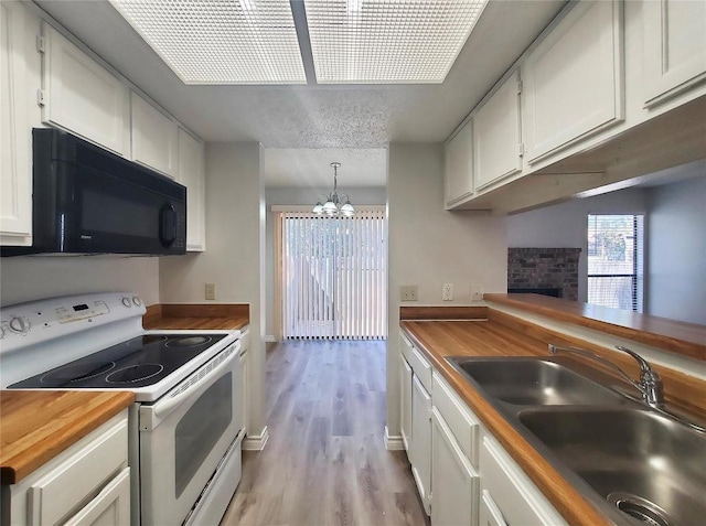 kitchen with black microwave, butcher block counters, a fireplace, a sink, and white electric range oven