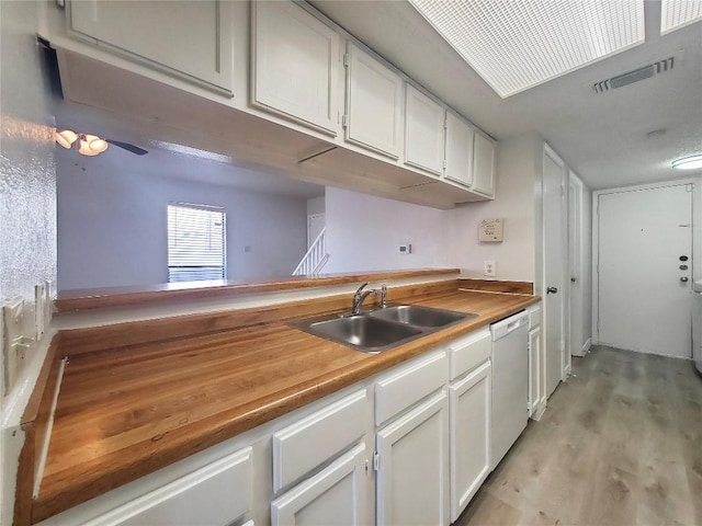 kitchen featuring butcher block counters, visible vents, white cabinetry, a sink, and dishwasher