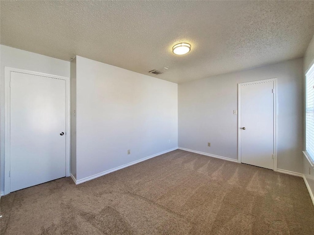 unfurnished bedroom featuring a textured ceiling, carpet, visible vents, and baseboards