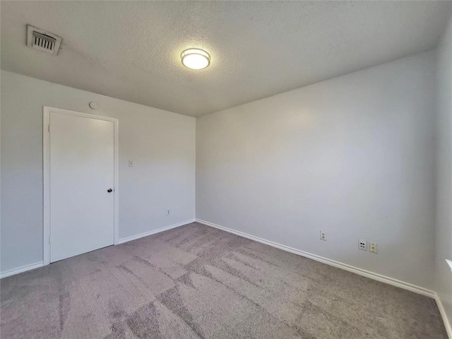 carpeted empty room featuring visible vents, a textured ceiling, and baseboards