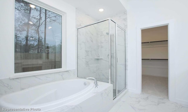 bathroom with a stall shower, marble finish floor, a walk in closet, a bath, and recessed lighting