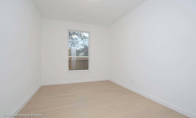 spare room featuring baseboards and light wood finished floors