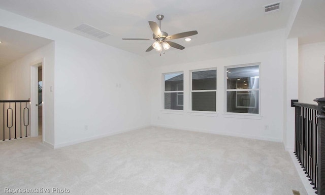 spare room with light carpet, baseboards, visible vents, and ceiling fan