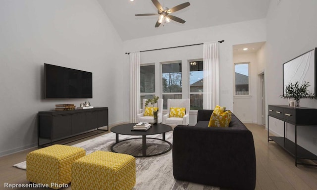 living room featuring high vaulted ceiling, wood finished floors, a ceiling fan, and baseboards