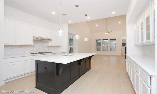 kitchen featuring light countertops, white cabinets, a sink, and under cabinet range hood