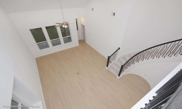 stairway with high vaulted ceiling, ceiling fan, visible vents, and wood finished floors