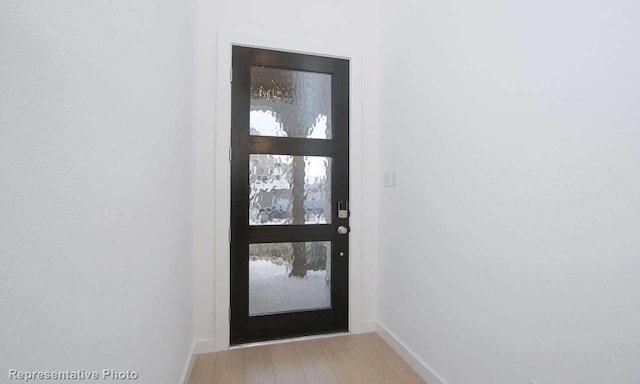 doorway to outside featuring light wood-style flooring and baseboards