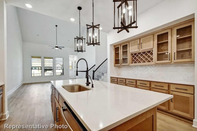 kitchen with stainless steel dishwasher, light wood-style floors, light countertops, and a sink