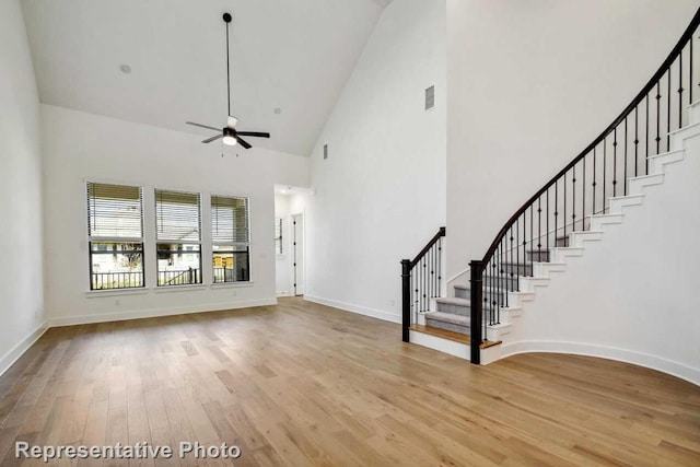 unfurnished living room featuring stairs, light wood-style floors, visible vents, and a ceiling fan