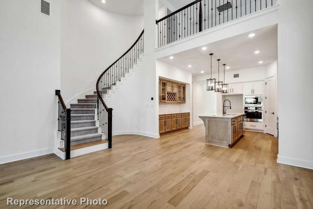 interior space with light wood-style flooring, a high ceiling, visible vents, appliances with stainless steel finishes, and a sink