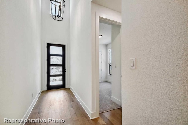 foyer entrance featuring a textured wall, wood-type flooring, and baseboards