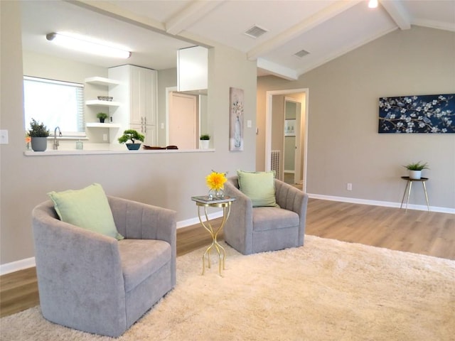 living area featuring lofted ceiling with beams, baseboards, visible vents, and wood finished floors