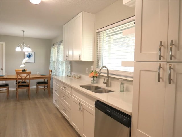 kitchen with wood finished floors, a sink, white cabinetry, light countertops, and stainless steel dishwasher