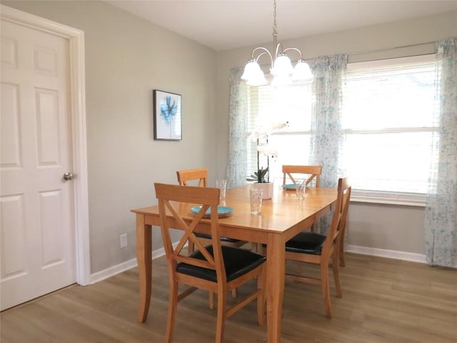 dining room with light wood finished floors, baseboards, and a chandelier