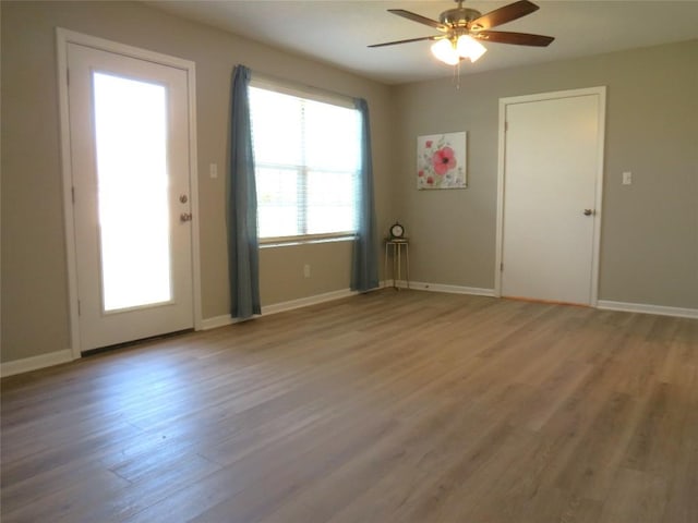 unfurnished room featuring a healthy amount of sunlight, ceiling fan, light wood-style flooring, and baseboards