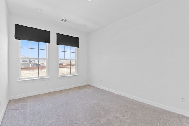 carpeted spare room featuring baseboards and visible vents