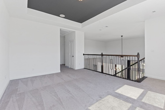 unfurnished room with carpet, baseboards, and a tray ceiling