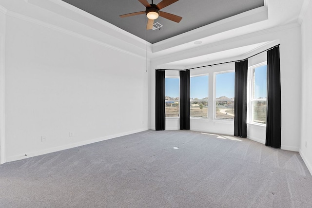 carpeted spare room with baseboards, visible vents, a ceiling fan, a raised ceiling, and crown molding