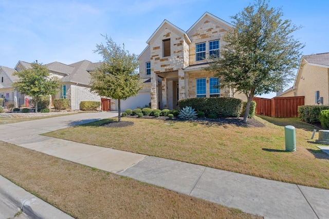 view of front of property with driveway, stone siding, fence, and a front lawn