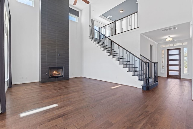 unfurnished living room with stairs, plenty of natural light, wood finished floors, and visible vents