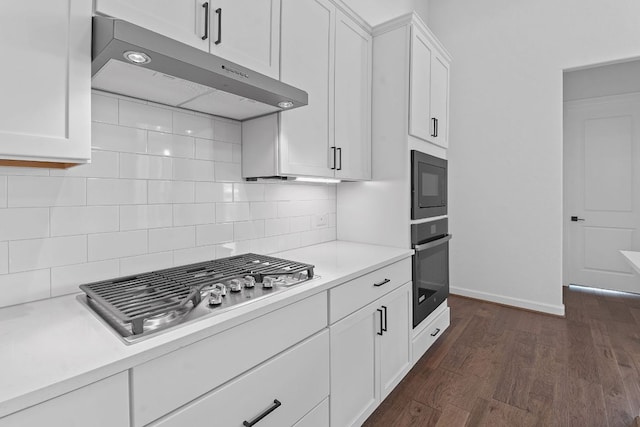 kitchen featuring under cabinet range hood, light countertops, black appliances, tasteful backsplash, and dark wood finished floors