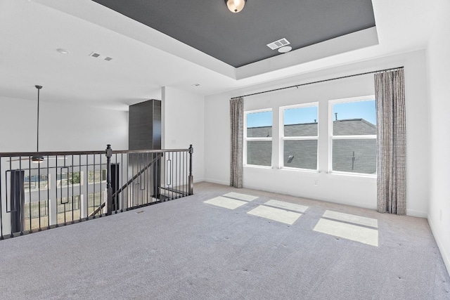 unfurnished room featuring carpet floors, a raised ceiling, and visible vents