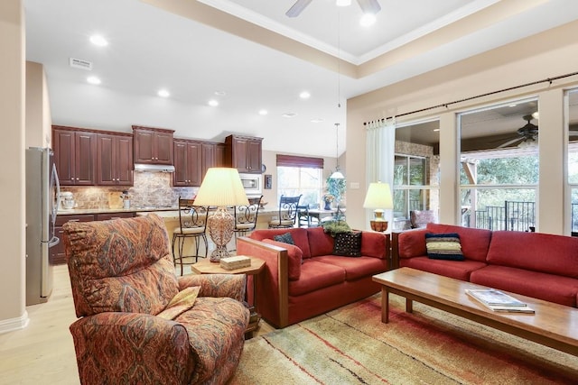 living area with ceiling fan, light wood-style flooring, recessed lighting, visible vents, and crown molding