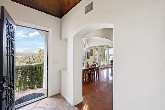 foyer featuring arched walkways, light wood-style flooring, visible vents, baseboards, and french doors