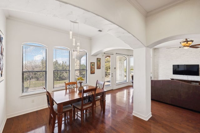 dining area with a wealth of natural light, ornamental molding, arched walkways, and wood finished floors