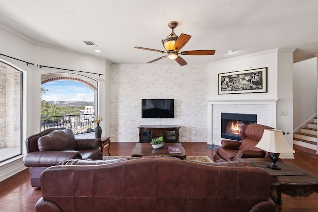 living area featuring wood finished floors, a fireplace with flush hearth, visible vents, stairs, and a ceiling fan